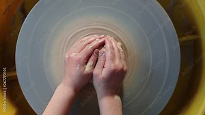 top view kids Hands working on pottery wheel, shaping a clay pot. Children Making Pottery In Workshop, potter's wheels in the pottery workshop