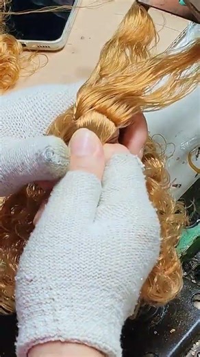 the process of attaching hair to a Barbie doll using a machine