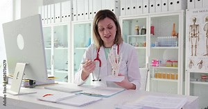 Doctor traumatologist orthopedist holds anatomy of bones of palm and fingers in clinic. Specialist demonstrates human hand bone structures