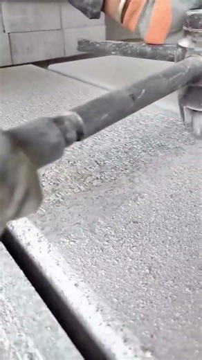 smoothing a rough stone slab by rolling a heavy textured metal tool across its surface meticulously