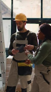 Vertical video Chief logistics officer and employee preparing warehouse orders for delivery, using tablet to verify shipping informations, receiving phone call while scanning parcels labels in