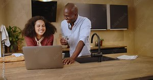 Young couple using a laptop in their kitchen