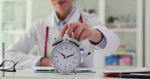 Doctor sets alarm clock at ten in morning at clinic