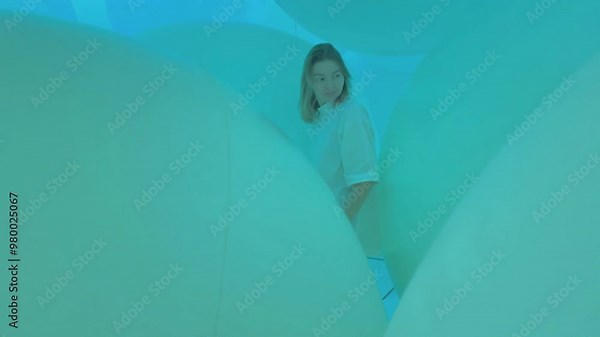 A woman is immersed in an ethereal cyan environment while exploring a captivating abstract space