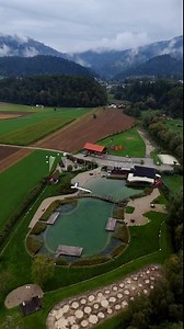 Vertical drone shot captures an eco-friendly natural swimming park and biological pool in Radlje ob Dravi, Slovenia, showing scenic water areas, green landscapes, and sustainable design 素材庫影片