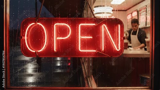 Atmospheric red neon OPEN sign on a rainy window with a worker inside the diner at night