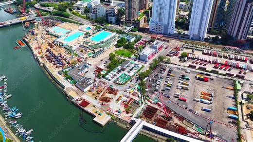 Aerial skyview of Tuen Mun subway extension project in Hong Kong, featuring elevated railway construction along Tuen Mun River and road, new station development and temporary work platforms