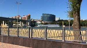 Embankment with a beach by the river. Beautiful big bridge. City on a sunny day.