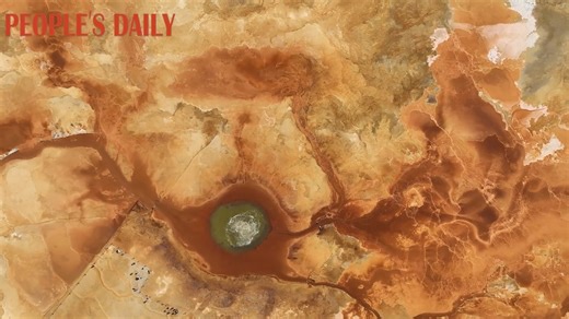 31K views · 290 reactions | Aiken Spring, a natural wonder in the Gobi desert in northwest China's Qinghai, bubbles up water with a high sulfur content, rendering the land around it barren. With a diameter of about 10 meters, the spring appears like a striking eye from a bird's-eye view, set against the reddish and yellow hues of the surrounding terrain. | People's Daily, China | Facebook