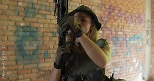 confident beautiful woman in hat loads a gun,prepares to shoot close-up slow motion. female soldier is aiming , leveling a rifle in the building slow motion camera motion Stock Video
