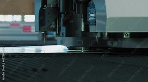 Hydraulic punching press machine is operating at an industrial factory. Punching press machine is creating multiple holes in the long steel sheet. Modern punching press machine processing the material