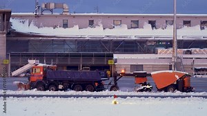 Snowplows truck working clearing snow at international airport terminal and runway. Bad weather, snow-clearing machinery in blizzard