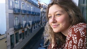 girl peeps out of hotel window looking at tourist city