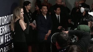 Angelina Jolie poses on the red carpet while Pax takes photos