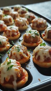 Mini Pizza Bites with Meatballs Cheesy Meatball Mini Pizza Delights Recipe Ingredients: For the Dough: 2 cups all-purpose flour 1 teaspoon baking powder 1/2 teaspoon salt 3/4 cup milk 2 tablespoons olive oil For the Topping: 12 small pre-cooked meatballs (store-bought or homemade) 1 cup pizza sauce 1 1/2 cups shredded mozzarella cheese 1/2 cup grated Parmesan cheese 1 teaspoon Italian seasoning Fresh basil leaves for garnish (optional) Directions: Preheat your oven to 400°F (200°C). Line a bakin