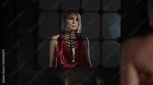 a young woman dressed in a bright colorful dress comes out of darkness and comes to the mirror, the lady sees her reflection and looks at herself from the side