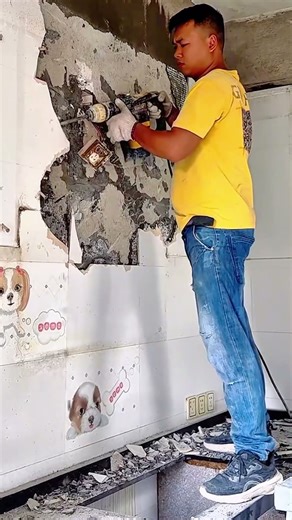 Worker demolishing interior wall using electric demolition hammer safely
