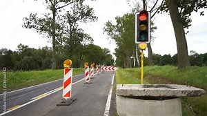 Road works with excavations marked with barriers and orange flashing warning lamps. Blocked street for traffic due to renovation.
