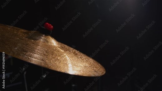 Water drops flying from drum kit. Drum player hits the cymbals of the drum set powerfully during the rock show on a stage under strobe flashes close up. Drummer playing the drums with drumsticks