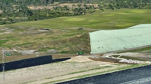 Solid waste disposal facility. Landfill dump site for garbage management. Bulldozer tractors burying large amount of trash under the ground. Harmful impact of modern consumerism on environment