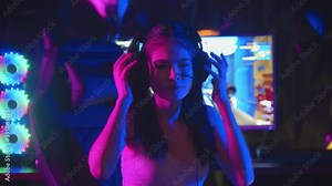 Young woman with pony tails playing a game in gaming club - put on her headphones and turns to the monitor