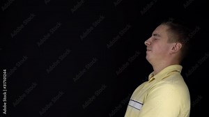 The man received a balloon in the face with water. A young man stands on a black background. A balloon filled with water hit the man in the face. Slow motion. FHD
