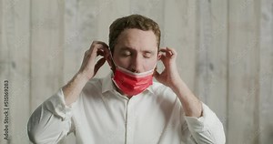 attractive young man shows how to properly put on a medical mask