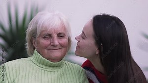 Beautiful teen girl hugging and kissing her grandmother smiling, slow motion