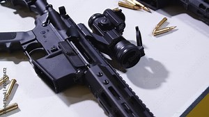 Pan shot of a tactical rifle with a sight and some ammunition.