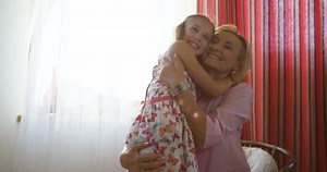 Granny sitting on couch next to her granddaughter and looking through photo album