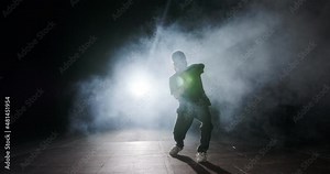 Teenage female dancer performing hip hop dance in slow motion with strobe light and smoke background