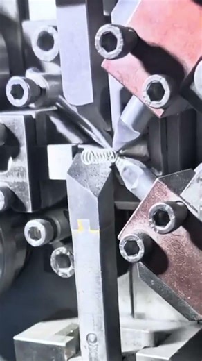 Manufacturing a small metal spring using an automated industrial machine with precise steel tools