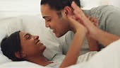 Love, bed and couple kissing and bonding in bedroom, talking, playful...