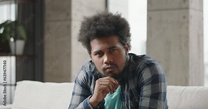 Video chat with black young man. African-American young black man conducts pleasant friendly informal video chat video call, looks at camera, listens attentively, laughs and smiles happily cheerfully.