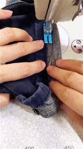 sewing a dark blue fabric edge carefully using a professional machine for garment manufacturing