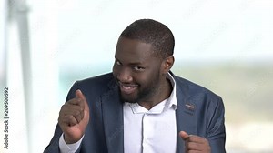 Funny man in business suit on blurred background. Handsome african-american guy in business suit showing funny facial expressions and gesturing with hands.