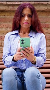 Woman sitting on stairs with cell phone in hands, writing messages and reading news online, using an app