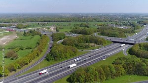 Aerial bird view flying over towards busy highway interchange with traffic driving in both directions on both sides of road showing cars and trucks beautiful day blue sky background 4k resolution