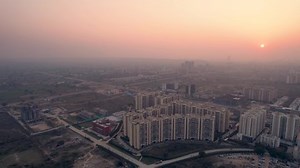flying towards aerial drone shot showing dust, fog, smog covered city at sunset dusk with crecent shaped apartment buildings stretching out into the distance showing population density in Indian