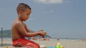 Kid playing sand with toy at the beach on summer vacation. Little child boy enjoy and have fun outdoor activity playing.