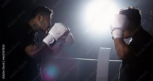 Two fighters inside ring staring at each other during combat wearing boxing gloves in dramatic lighting