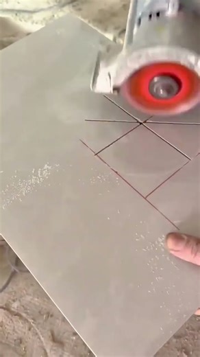 cutting out a precise circular hole from a light gray ceramic tile using a handheld power grinder