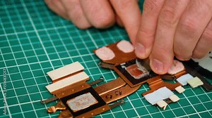 Cleaning old thermal paste from laptop heat sink components. Removing residue from copper surfaces during cooling system maintenance. Preparing heat sink by scraping off dried thermal compound for new