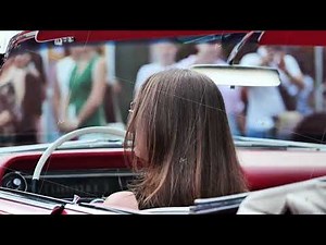 Young woman driving red convertible vintage car enjoying summer day