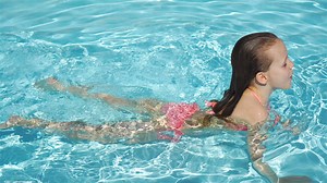 Cute little beautiful girl swim in outdoor swimming pool