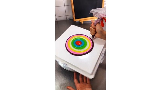 Layering brilliant rainbow circles across a glossy cake surface creating geometric dessert masterpiece