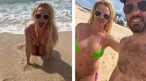 Britney Spears rolls in the sand wearing green and pink bikini