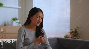 Charming asian woman painning form chest pain, Trouble breathing. Female has difficulty breathing or pain in chest touches chest with her hand. heart disease or leaky heart valve concept.