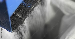 Crumb rubber granulate obtained on processing plant falling from machine. Small particles of rubber car tires on recycling factory. Recycled automobile tyres. Process of recycling, final product.