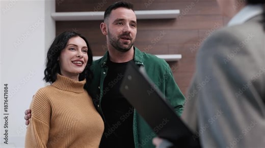 Couple engaged in a real estate transaction, smiling and interacting with an agent, exchanging documents and keys in a modern office setting with neutral colors and stylish decor